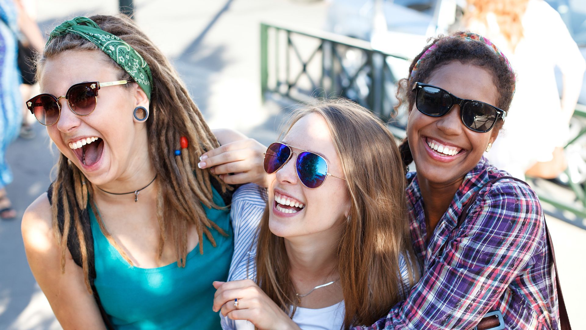 サングラスをかけ、一緒に微笑んで笑っている3人の女性のグループ。