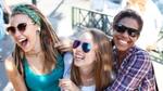 サングラスをかけ、一緒に微笑んで笑っている3人の女性のグループ。