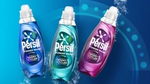 ティールを背景にしたブルー、ターコイズ、ピンク色を施した Persil Wonder Wash のボトル。